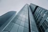 Low-angle view of modern, tall skyscrapers with blue-gray metal facades against a cloudy sky.