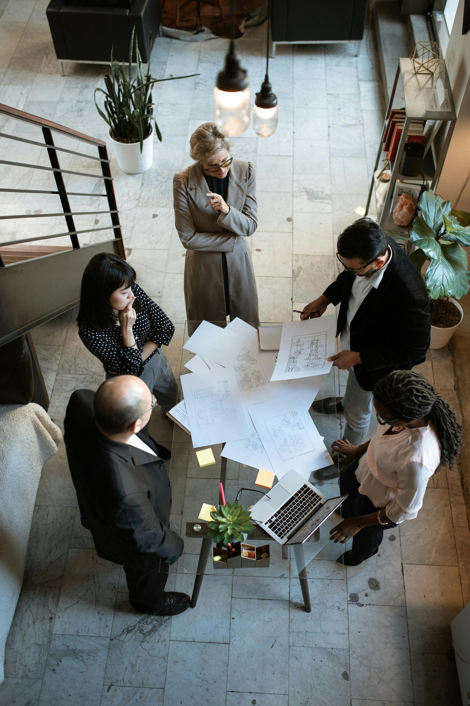 Business team in meeting, reviewing papers and laptop at table.