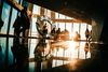 Skyscrapers' interior with a sunset view. Silhouetted figures stand around a decorative ring, reflecting on the shiny floor.