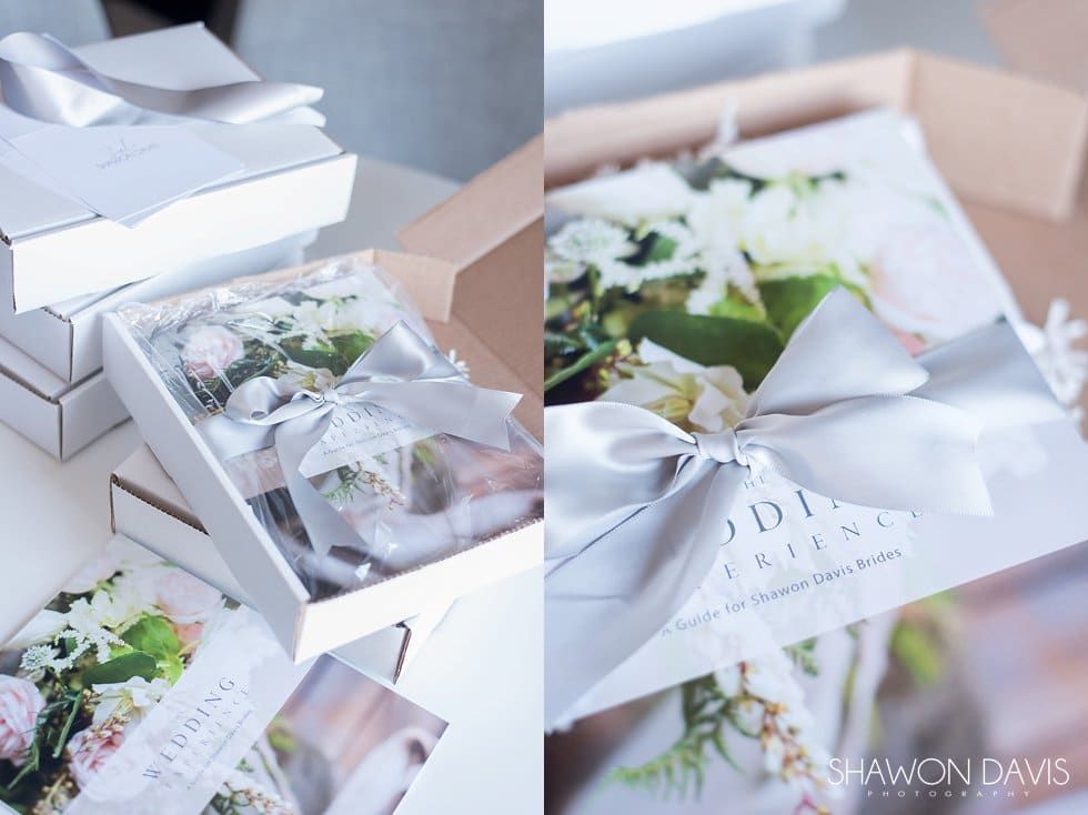 Stacked white gift boxes with floral arrangements and sheer ribbons on a table
