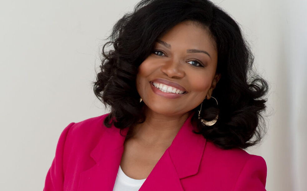 Smiling woman in a bright pink blazer against a light background