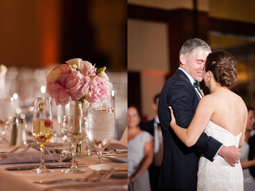 Bride and groom slow dance at a wedding reception beside a pink floral centerpiece