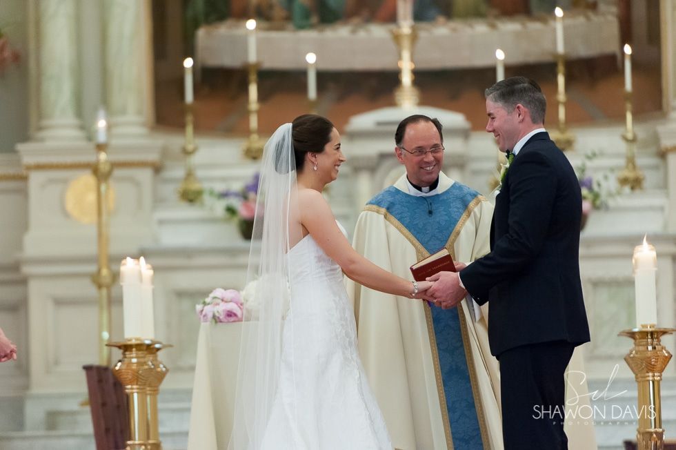 Bride and groom exchange vows with a priest at the altar in a church ceremony