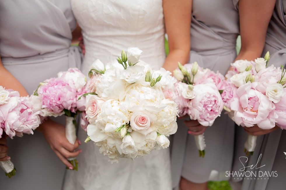 Bridesmaids holding pastel pink and white bouquets at a wedding