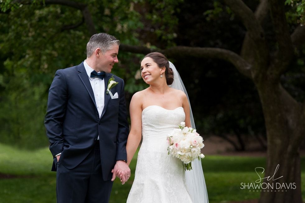 Bride and groom holding hands and smiling outdoors in a garden wedding setting