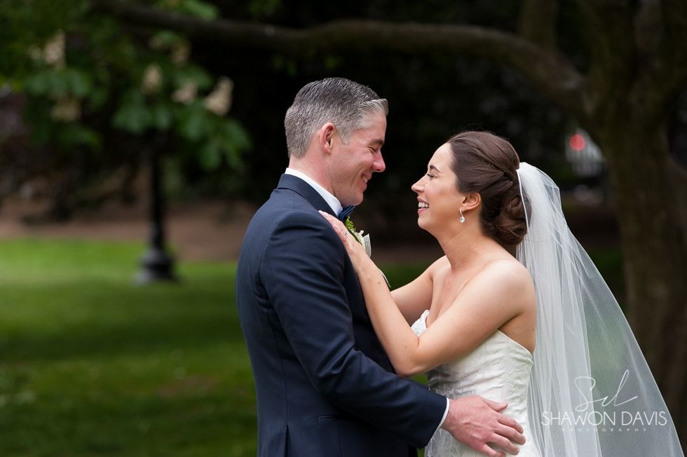 Bride and groom smiling and embracing outdoors in a green park during a wedding ceremony