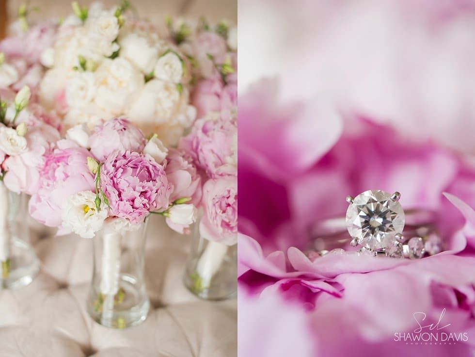 Wedding rings on a pink flower petal with soft-focus pink and white blossoms in the background