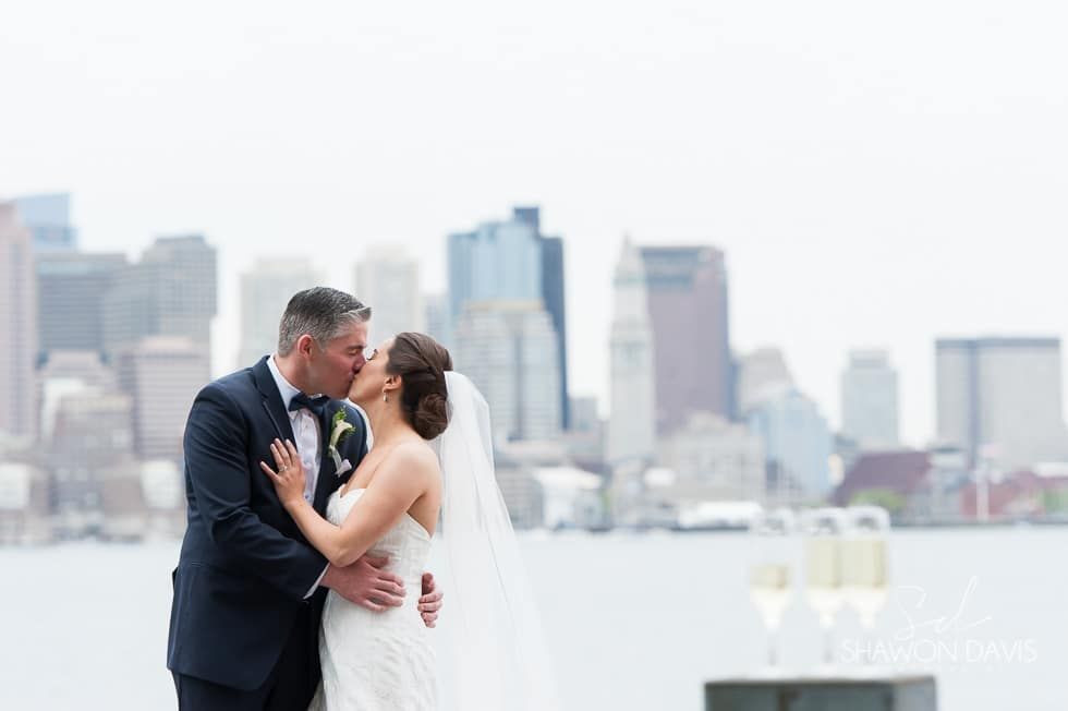 Bride and groom kissing on a rooftop with city skyline in the background