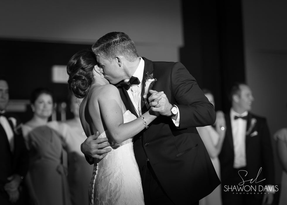 Bride and groom dancing closely at a wedding reception, in black and white.