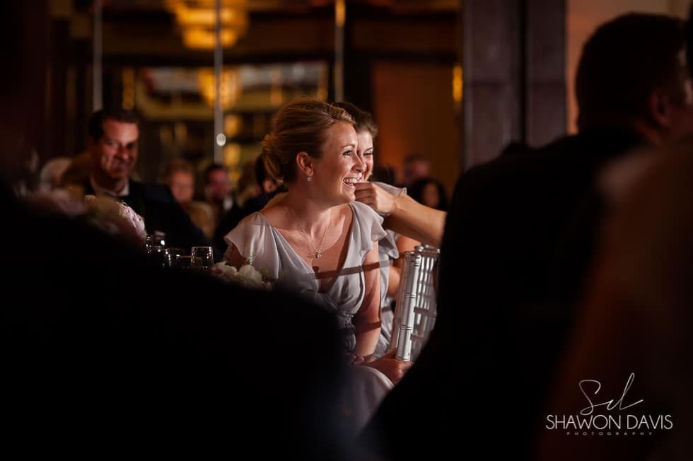 Guests seated at a warmly lit event, one woman smiling and talking at a table