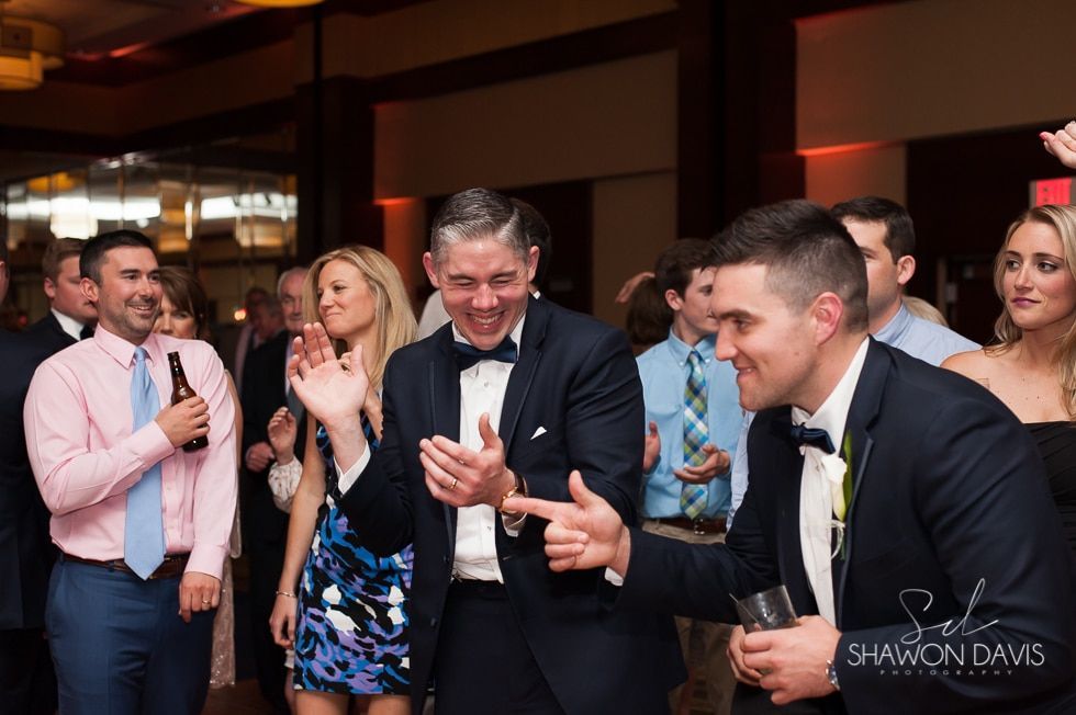 Guests applauding and smiling at a lively indoor event, with a man in a suit clapping in the foreground