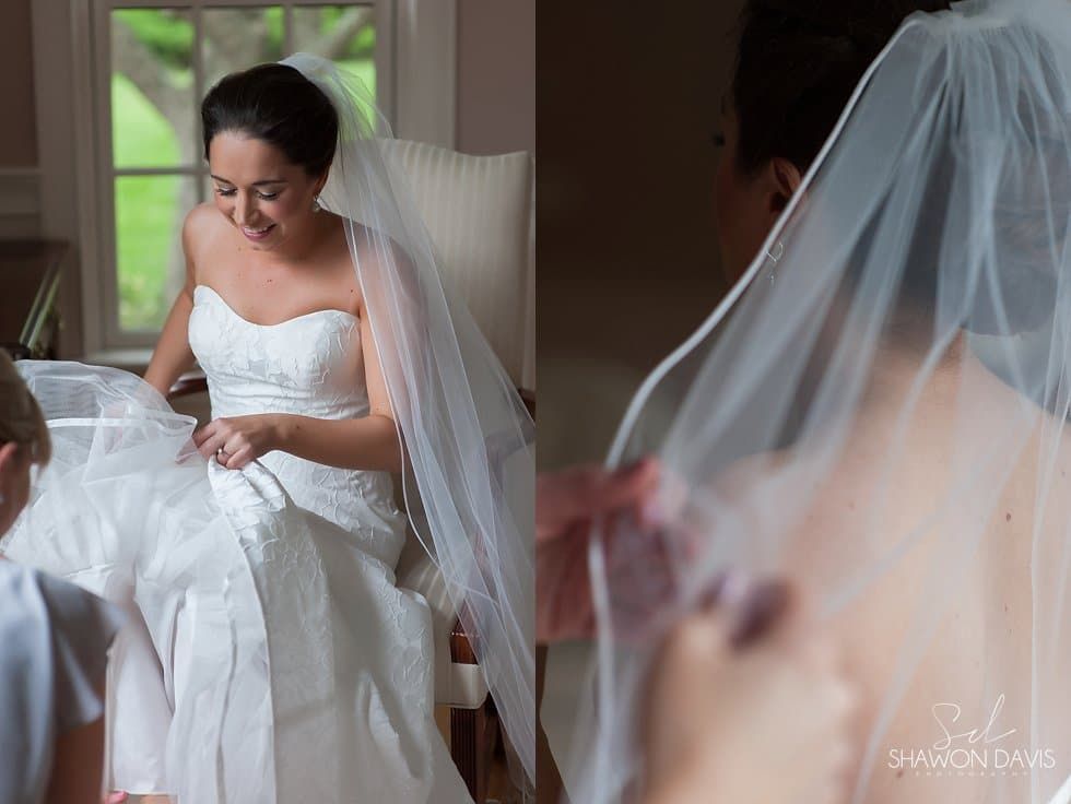 Bride in white wedding dress and veil, smiling while getting ready by a window