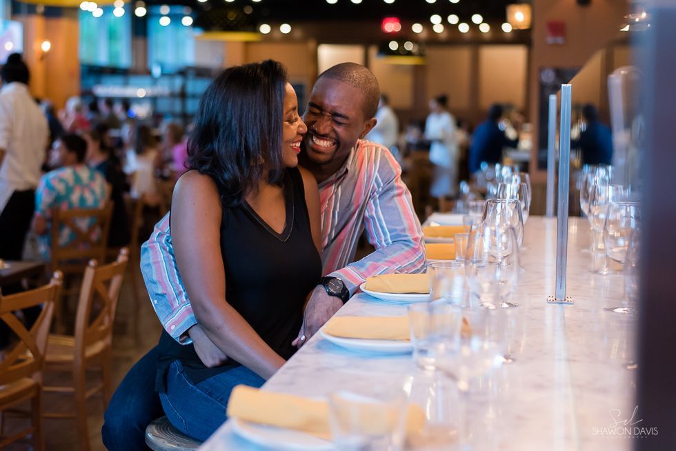 Couple smiling at a restaurant table with glasses, plates, and soft warm lighting