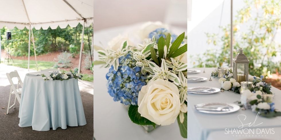 Elegant outdoor wedding table with pale blue linens, white flowers, and blue-and-white floral arrangements under a tent
