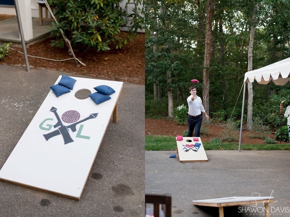 Outdoor cornhole game with a woman standing by a board and beanbags on a sloped lawn