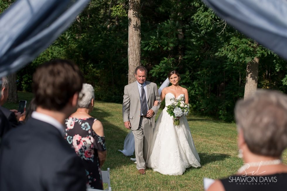 Bride and groom walk down an outdoor aisle during a garden wedding ceremony