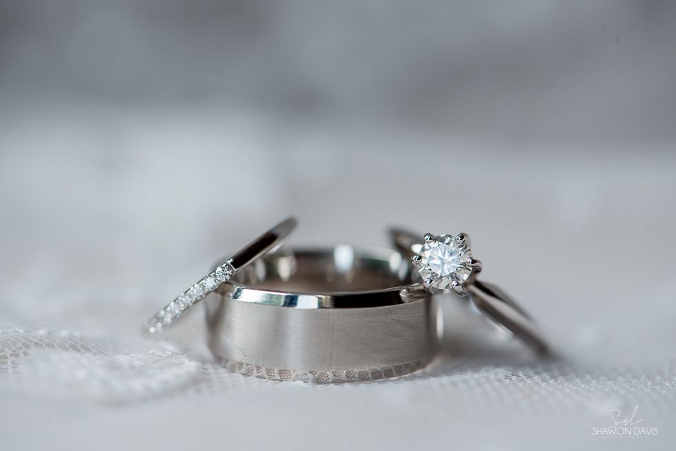 Two silver wedding rings with diamond accents on a soft gray surface