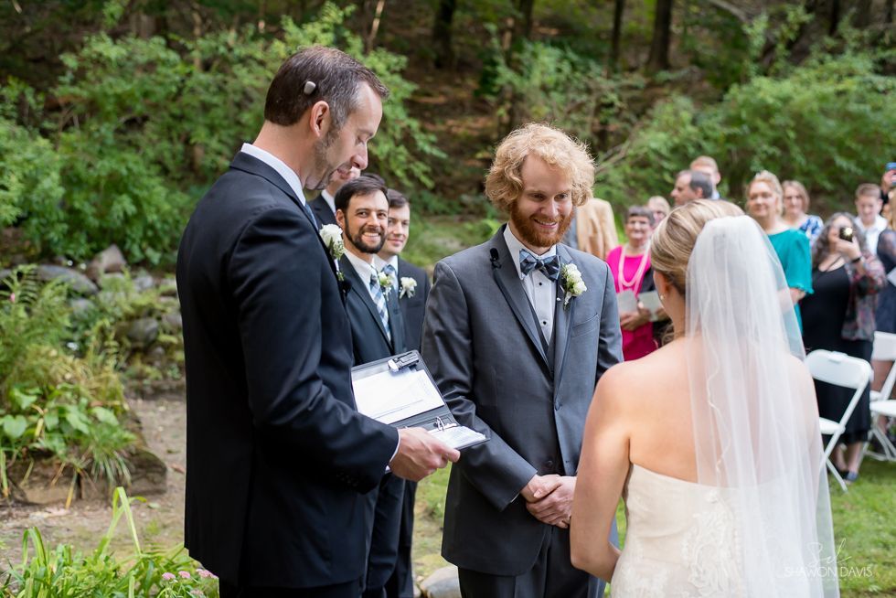Outdoor wedding ceremony with officiant reading vows to a bride and groom in front of seated guests