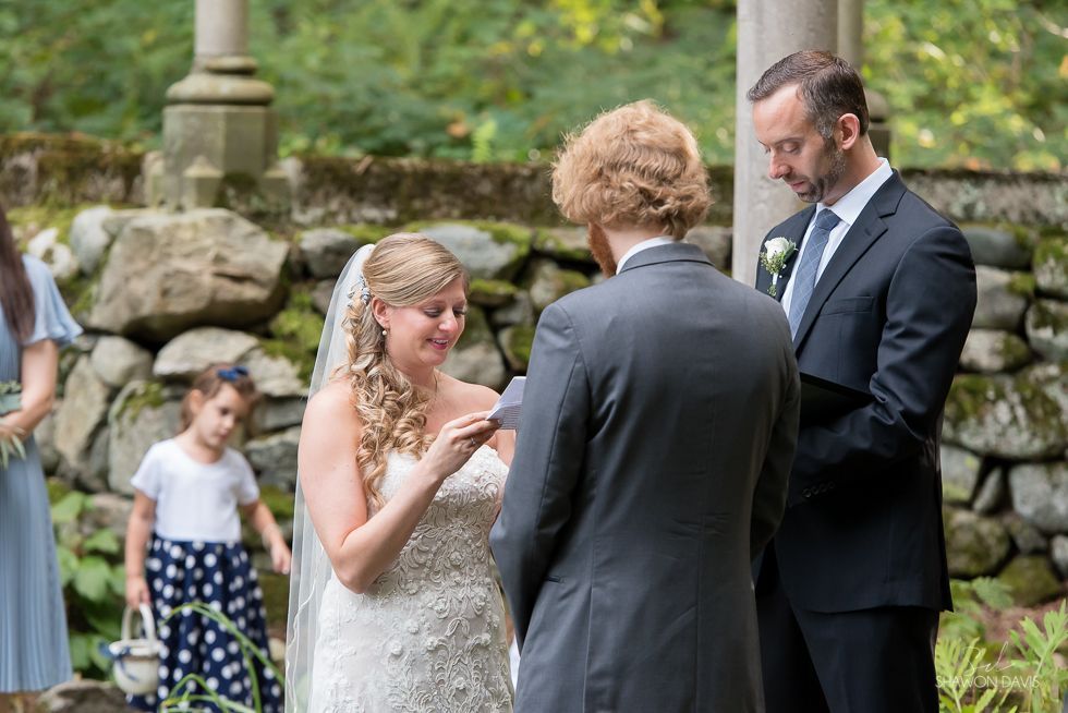 Bride and groom exchanging rings during an outdoor wedding ceremony in a garden