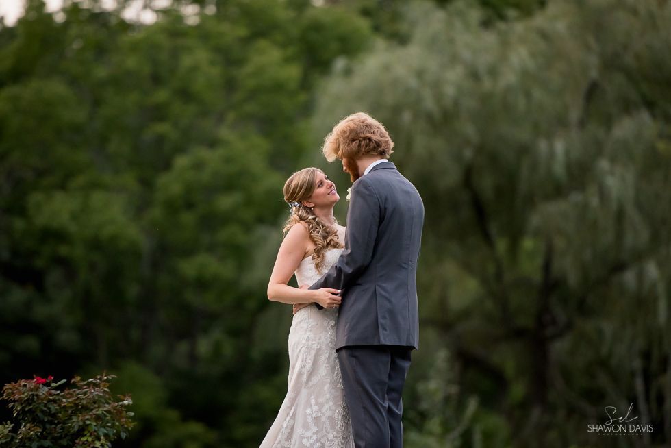 Couple in formal attire sharing a dance in a green outdoor setting