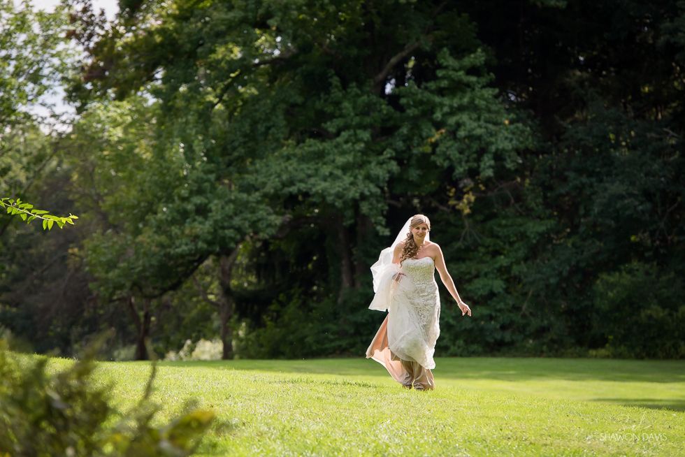 Woman in a white dress running through a sunny green park.