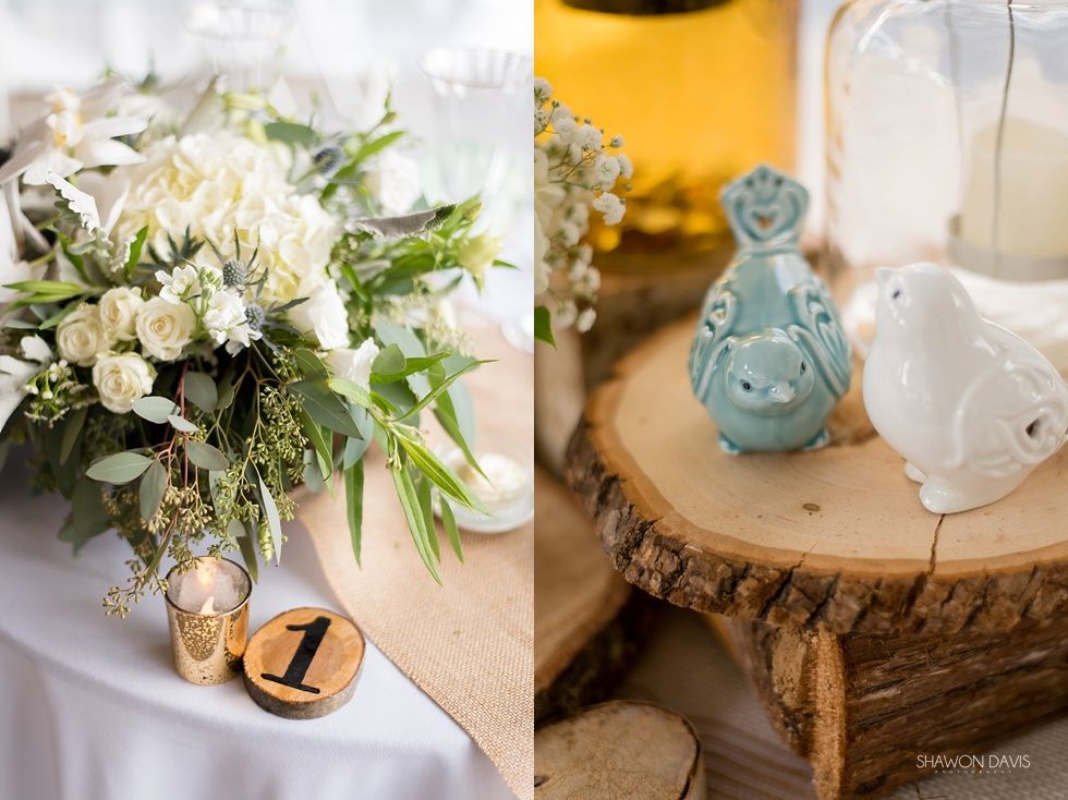 White floral bouquet with candles and ceramic bird figurines on a rustic wooden table