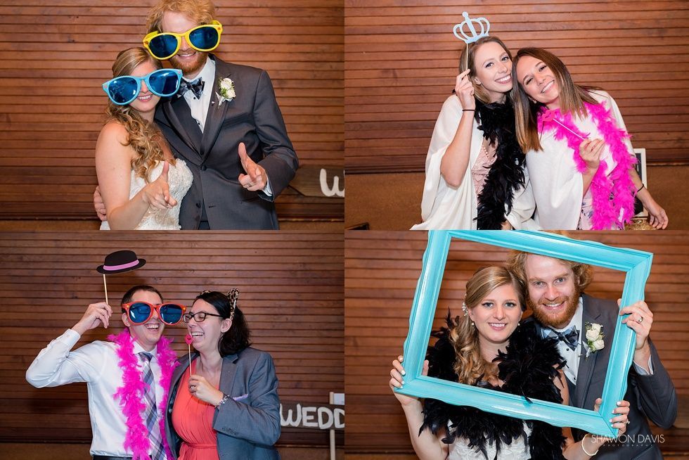 Four friends posing with oversized glasses and props at a wooden photo booth backdrop