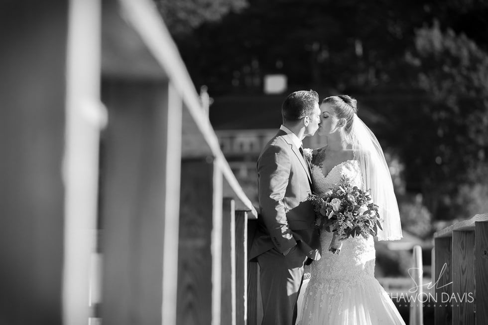Bride and groom kissing on a balcony in black-and-white wedding portrait
