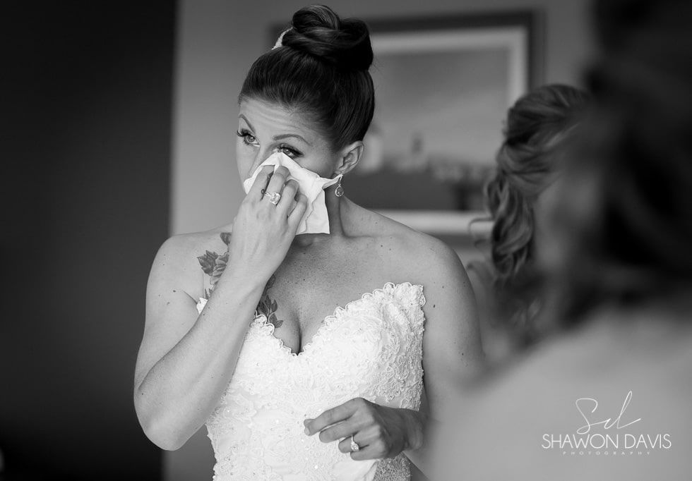 Bride wiping tears during emotional wedding moment in black and white photo