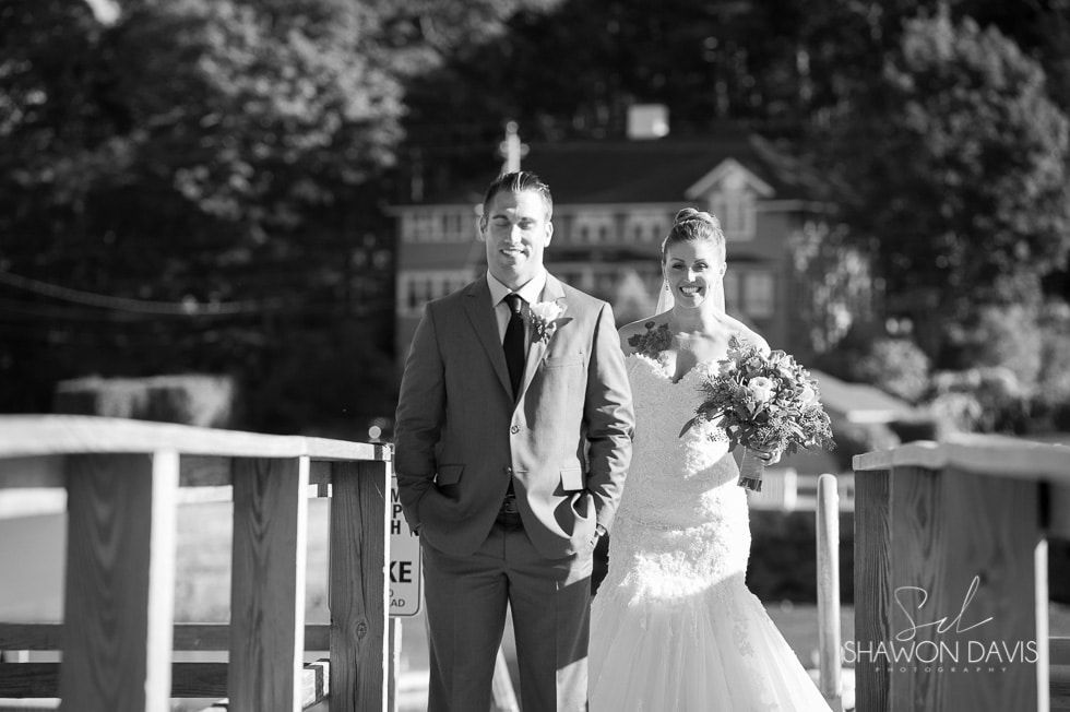 Wedding couple walking on a bridge, with the bride carrying flowers and the groom in a suit.