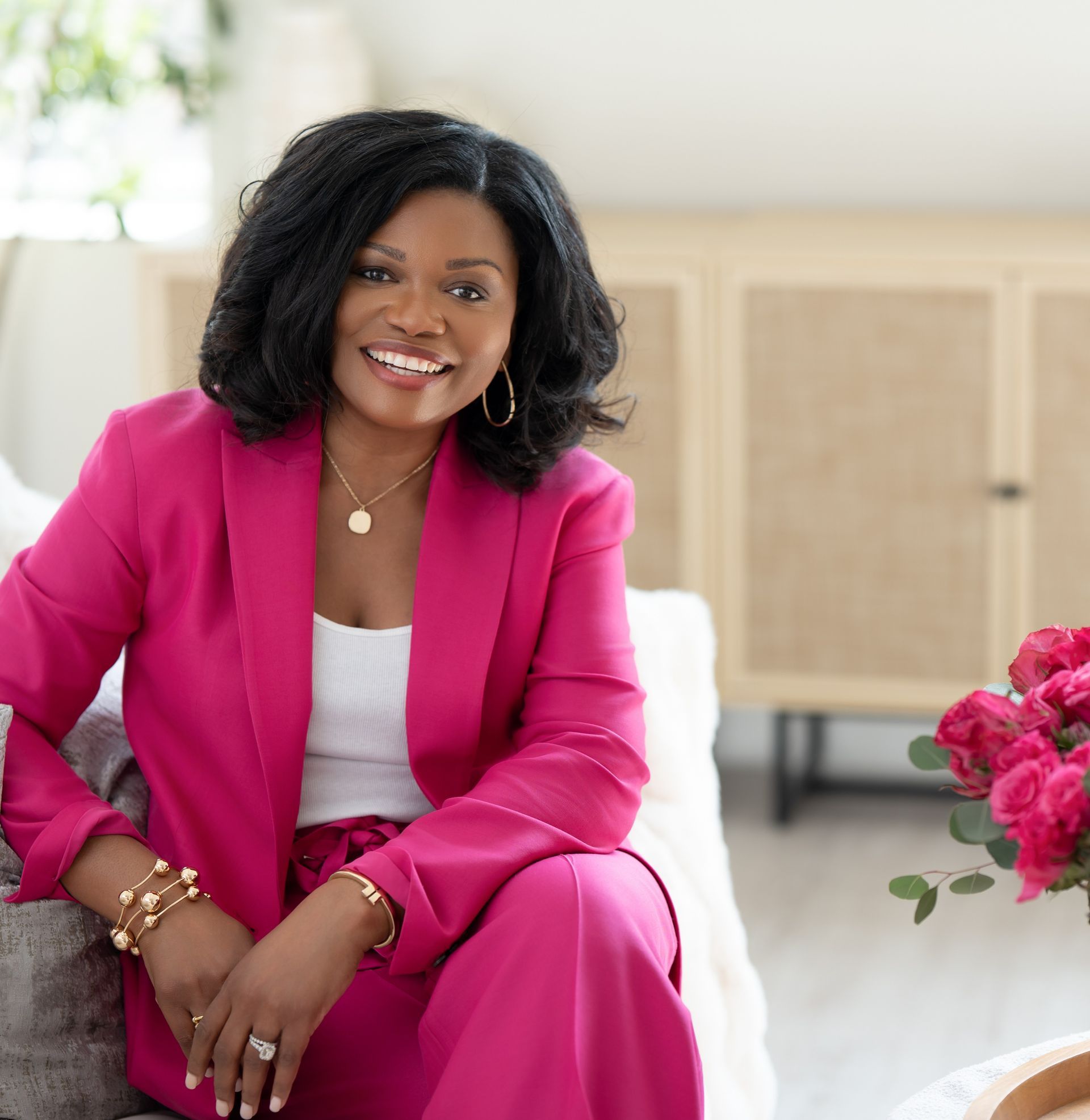 Smiling woman in a bright pink blazer posing against a plain light background