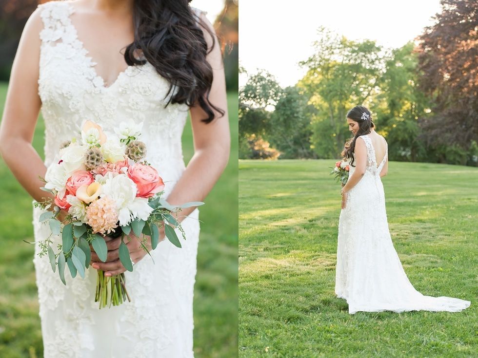 Bride in a white lace gown holding a bouquet in a sunlit grassy field at sunset