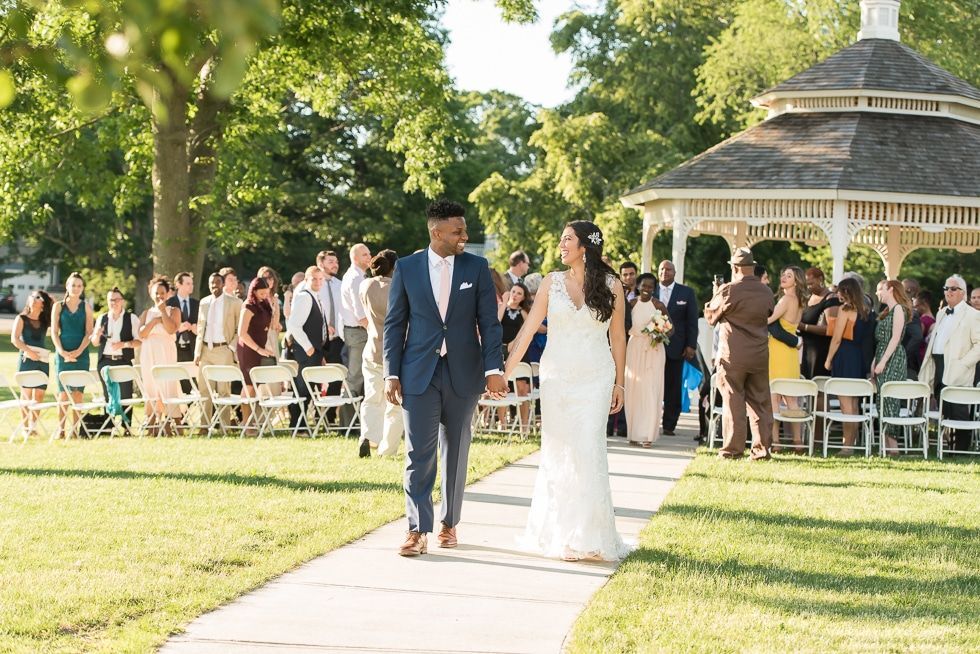 Bride and groom walking down an outdoor aisle at a garden wedding ceremony