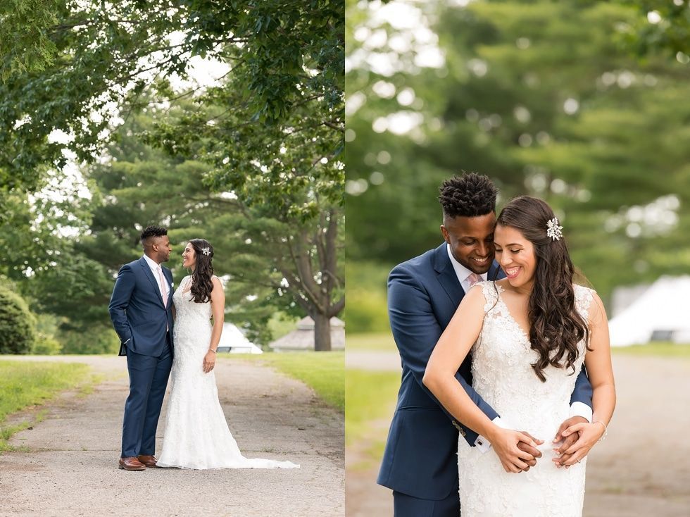 Two couples in wedding attire embrace on a tree-lined path, with one couple in focus smiling.