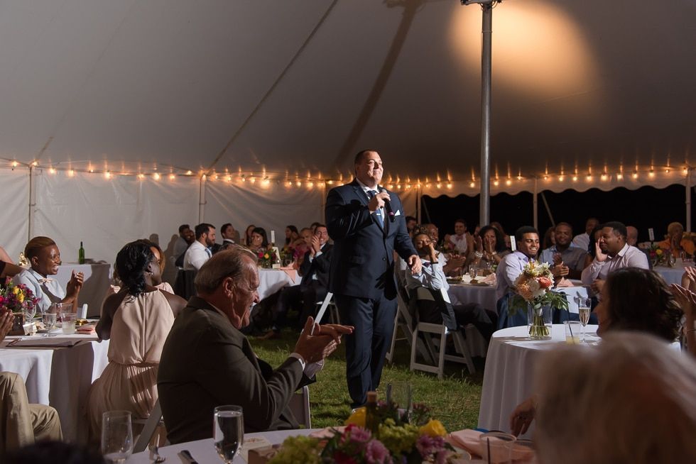Singer performing at a candlelit outdoor dinner reception under a tent