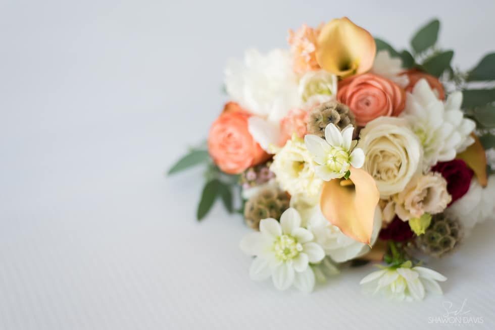 Pastel flower bouquet with white, peach, and cream blooms on a light gray surface
