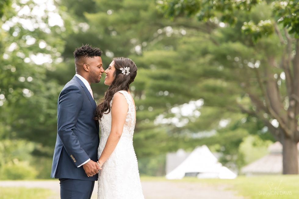 Bride and groom standing close and smiling in a green outdoor wedding setting