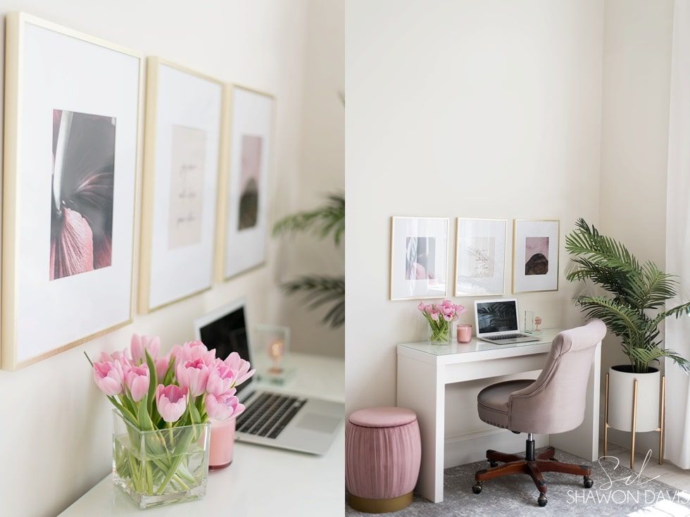 Bright minimalist home office with pink flowers, framed art, a desk, laptop, chair, and potted plants