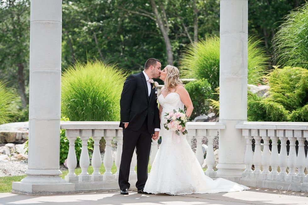 Bride and groom sharing a kiss in a white gazebo garden setting