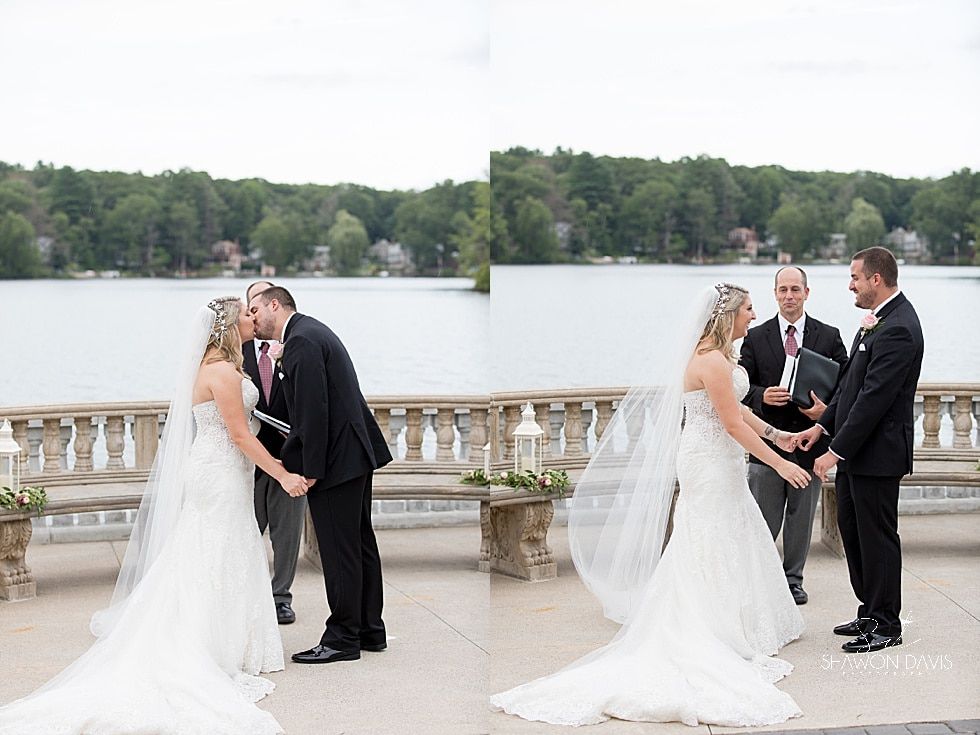 Two couples exchanging vows on a lakeside terrace, with a lake and trees in the background.