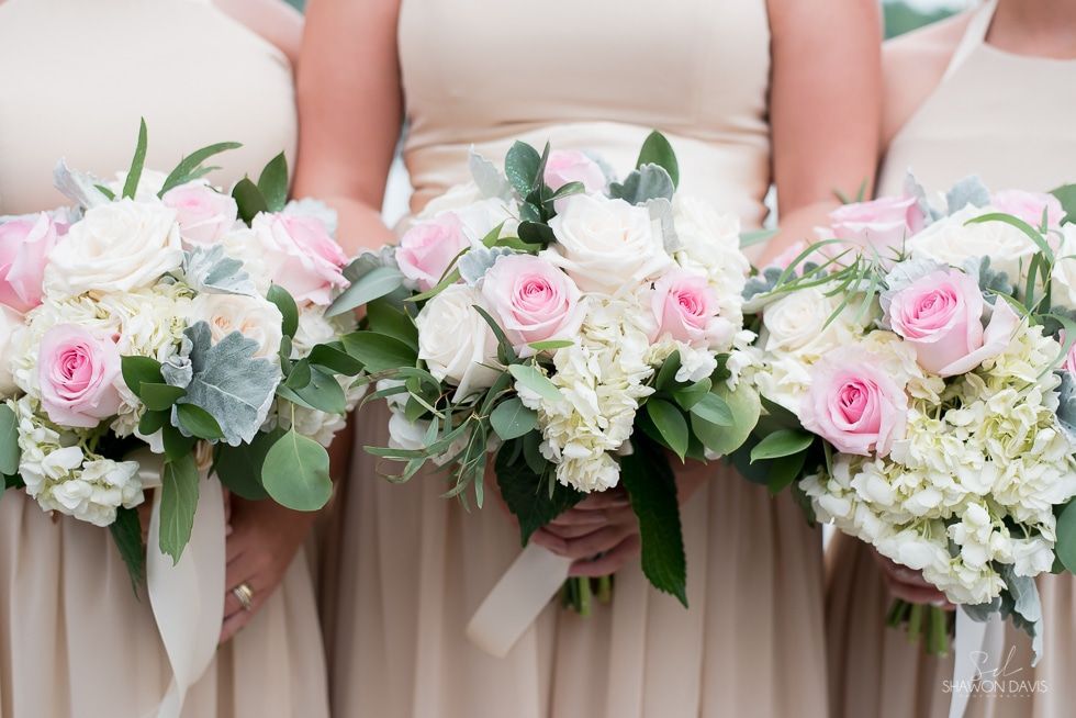 Three bridesmaids holding pastel pink and white flower bouquets