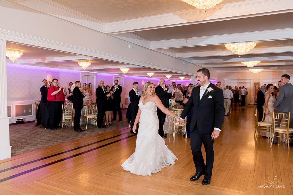 Bride and groom dancing at a wedding reception in a decorated ballroom.