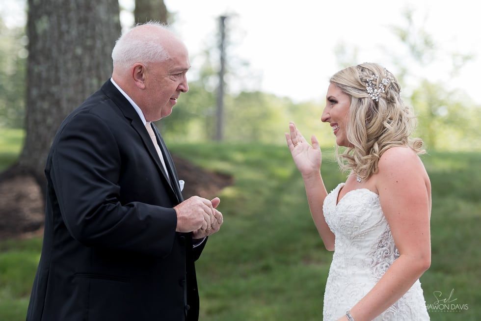 Bride in white gown and man in dark suit talking outdoors at a wedding ceremony
