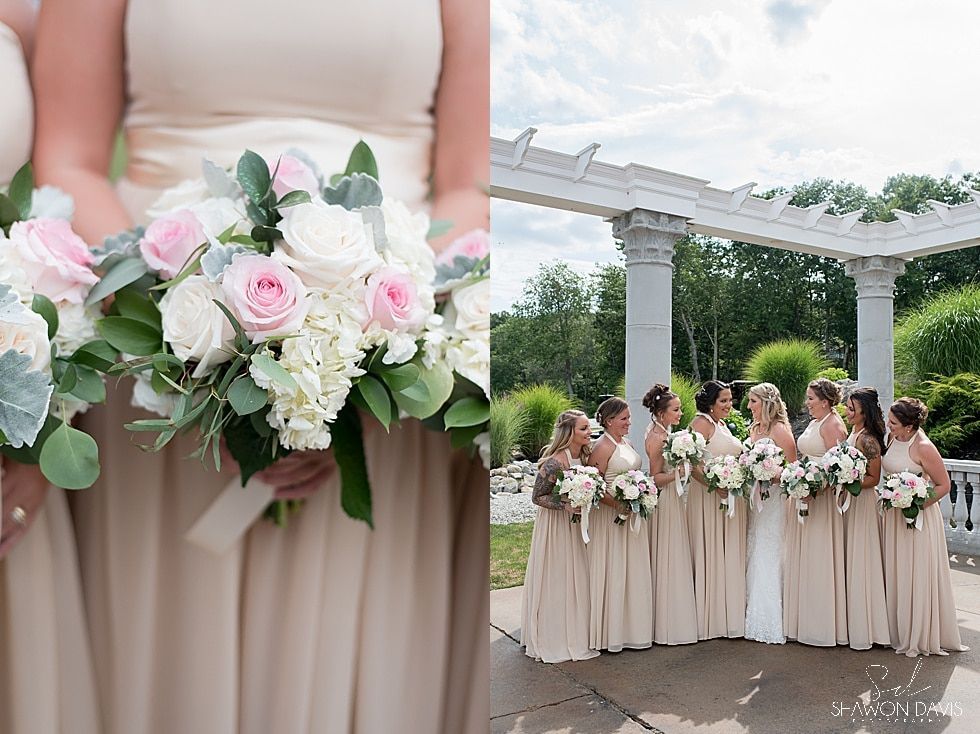 Bridesmaids in blush dresses holding white and pink bouquets under a garden pergola