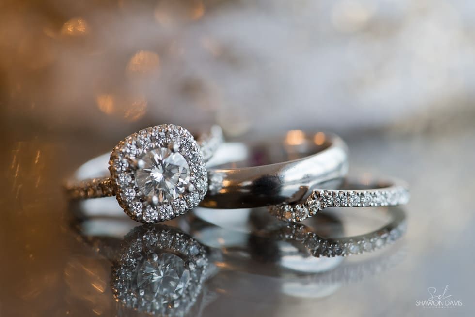 Three diamond rings on a reflective surface with a soft, blurred background