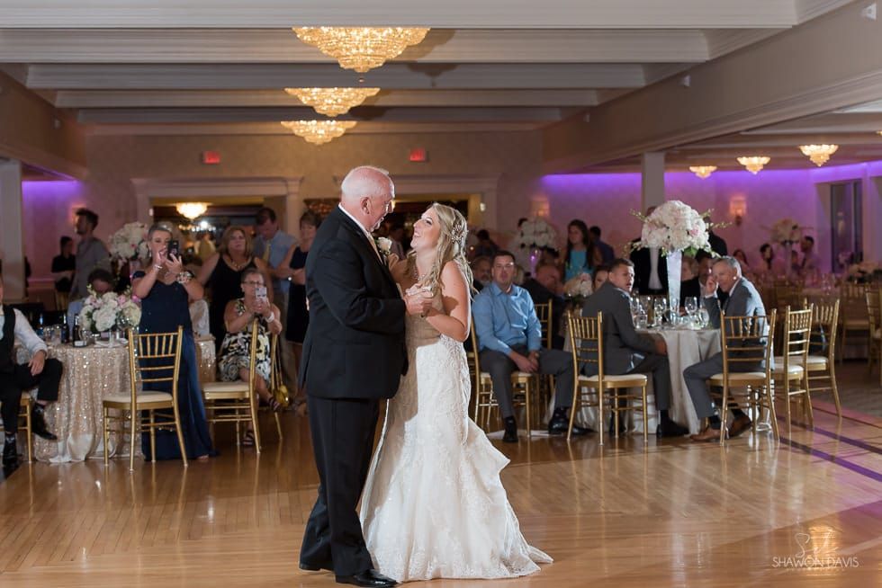Couple dancing at a wedding reception in a ballroom with guests seated nearby