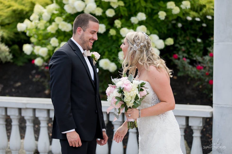 Bride and groom smiling and holding hands in a garden wedding setting