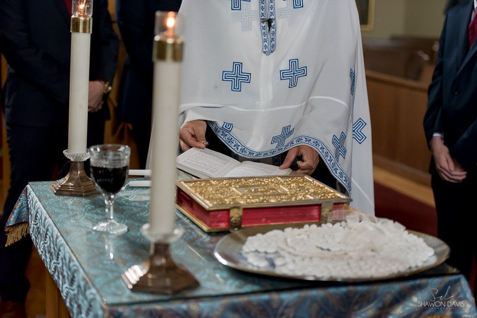 Priest at altar with open book, candles, chalice, and communion wafers on a blue cloth