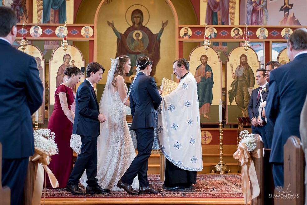 Wedding ceremony in a church, with the couple standing before a priest at the altar.