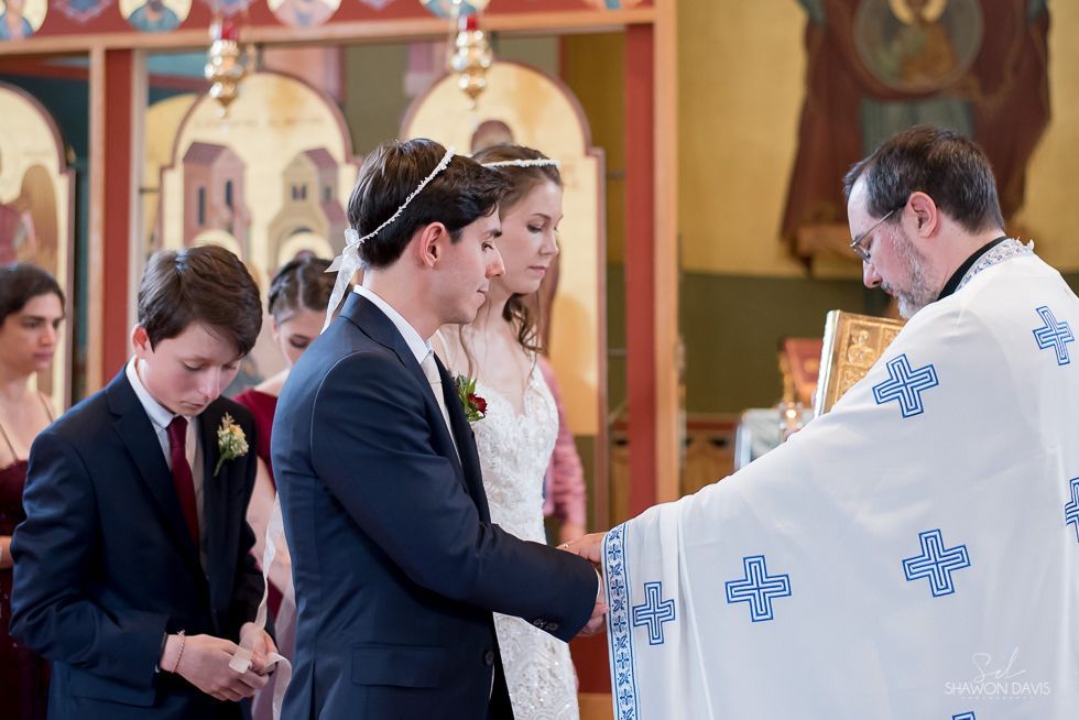 Wedding ceremony in a church, with a priest blessing the couple at the altar.